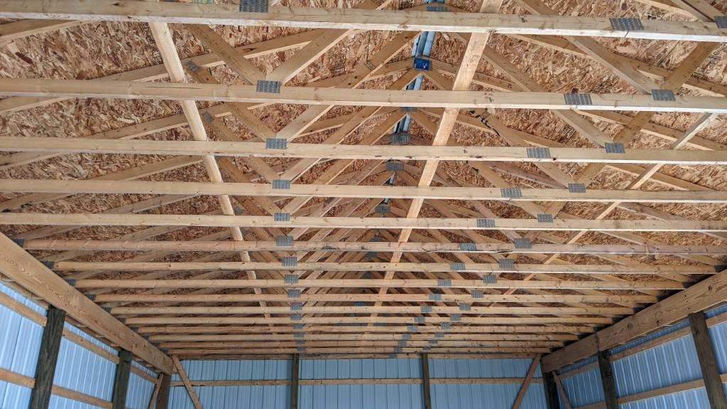 Interior roof truss view of a blue pole barn under construction