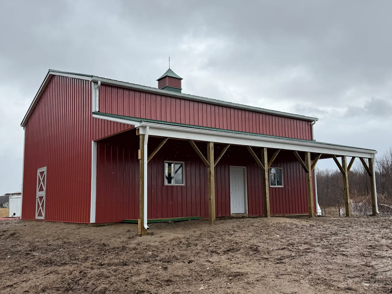 Red post-frame barn with lean-to porch and cupola, a CNO build
