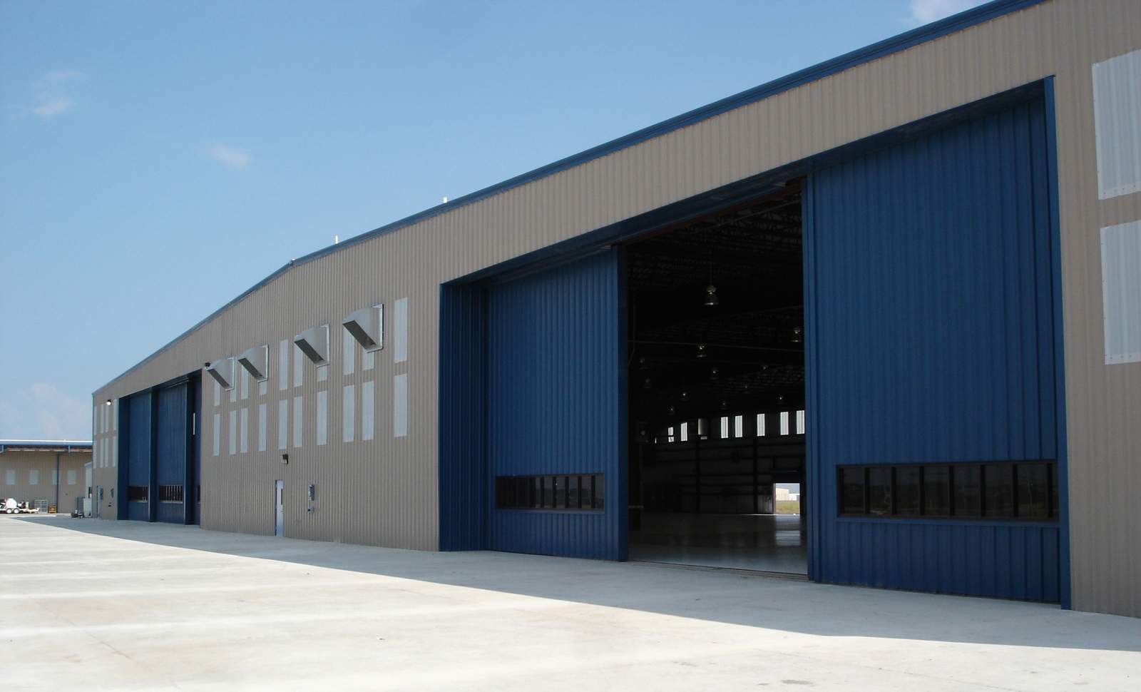 Large tan and blue pre-engineered steel aircraft hangar