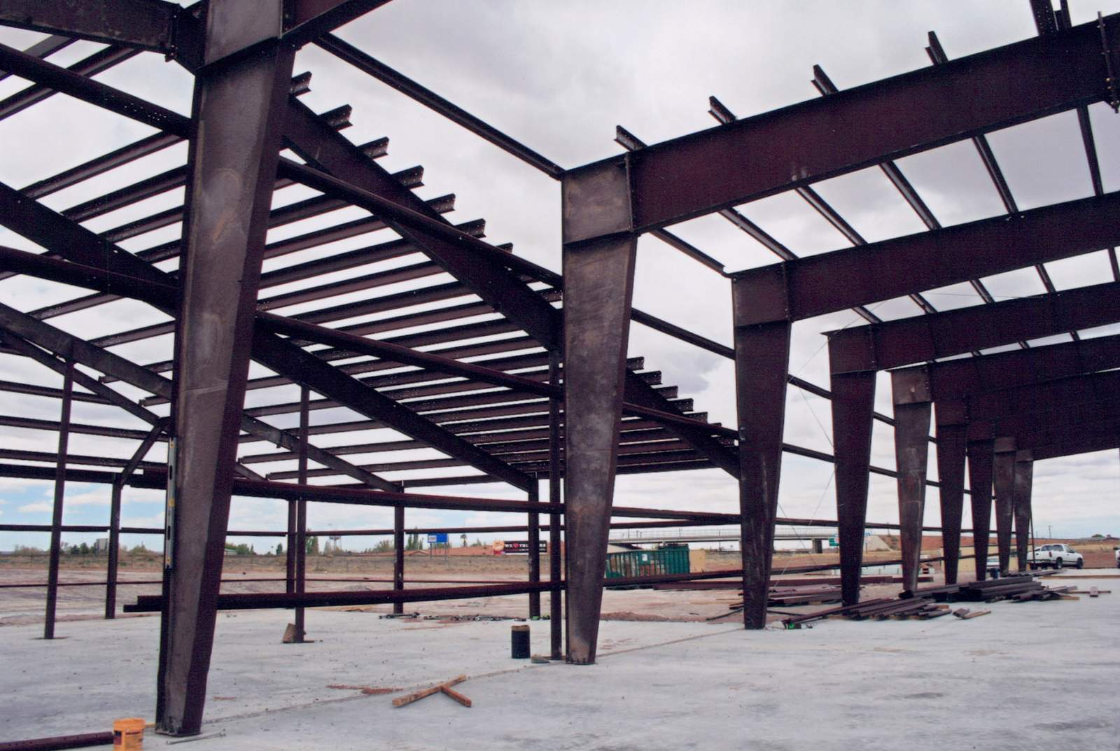 Steel I-beam frame of a commercial building under construction on a poured concrete slab