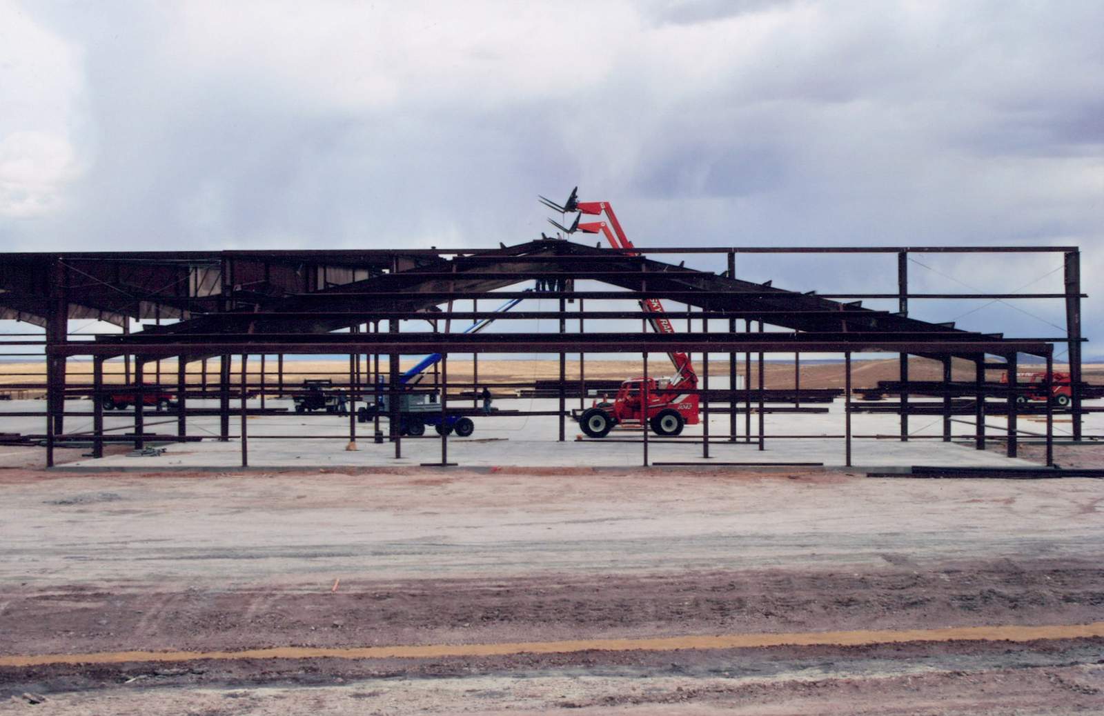 Rust-primed steel frame of an industrial building under construction, boom lift on site