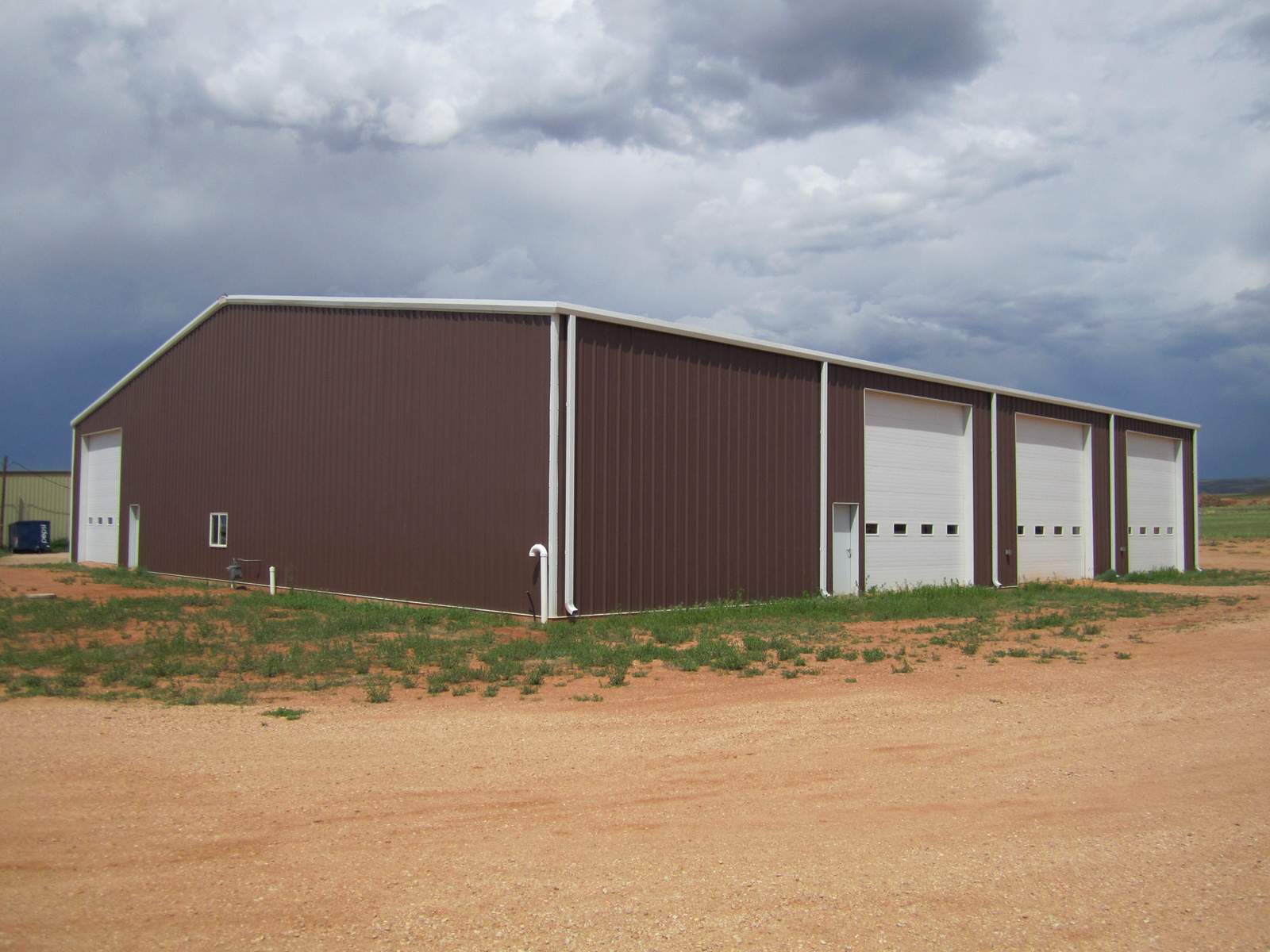 Brown steel shop building with three white overhead doors